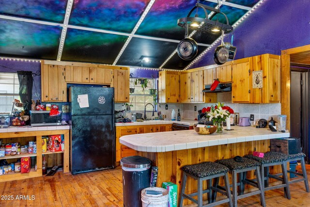 1326 W Apache Ln, Pinetop-Lakeside, AZ 85929 - kitchen featuring freestanding refrigerator, stainless steel microwave, tasteful backsplash, and light wood finished floors