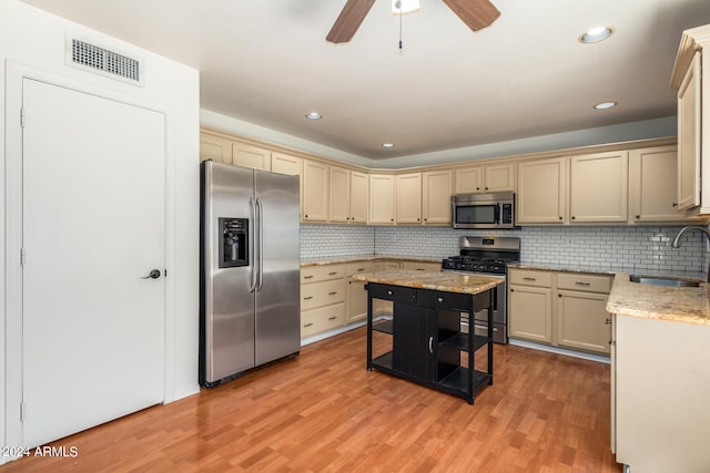 kitchen featuring stainless steel appliances, sink, decorative backsplash, ceiling fan, and light wood-type flooring