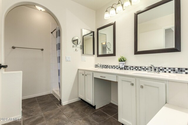 bathroom with vanity, tasteful backsplash, and a shower