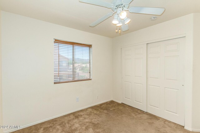 unfurnished bedroom featuring a closet, ceiling fan, and light carpet