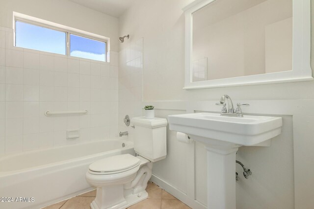 full bathroom featuring toilet, tiled shower / bath combo, sink, and tile patterned floors