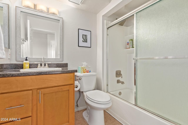 full bath featuring tile patterned floors, toilet, vanity, and bath / shower combo with glass door