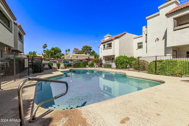 pool with a residential view, a patio, and fence