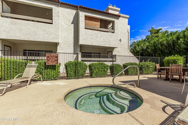 view of swimming pool with a hot tub, a patio, and fence