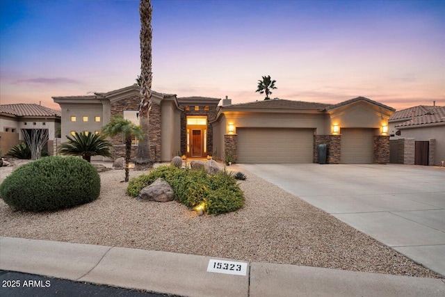 view of front of home with concrete driveway, an attached garage, stone siding, and stucco siding