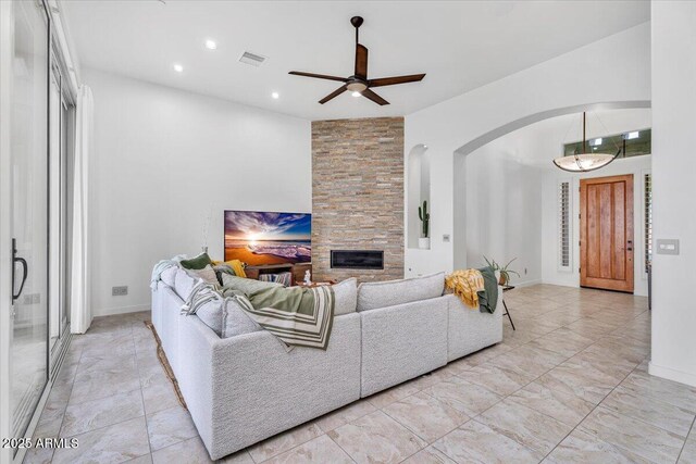 living area featuring visible vents, recessed lighting, arched walkways, ceiling fan, and a stone fireplace