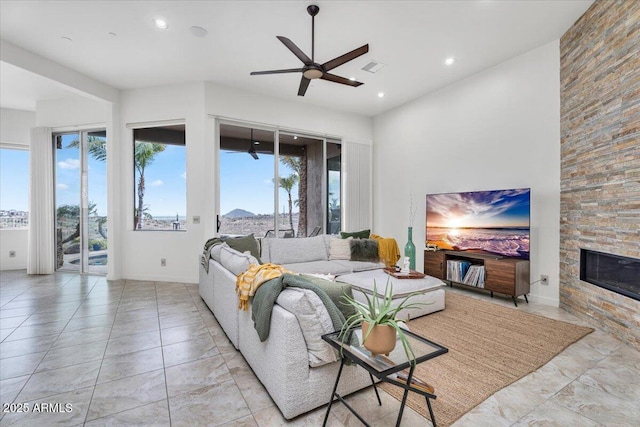 living room with a wealth of natural light, visible vents, a fireplace, and ceiling fan