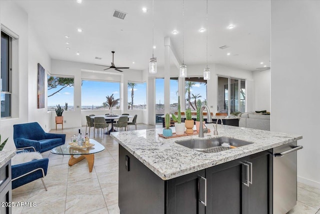 kitchen featuring a center island with sink, visible vents, open floor plan, and a sink