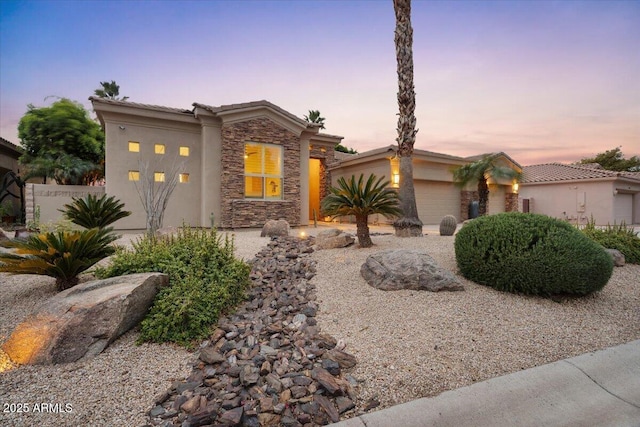 view of front facade with an attached garage, stone siding, and stucco siding