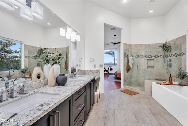 ensuite bathroom featuring a sink, connected bathroom, tiled shower, and a freestanding tub