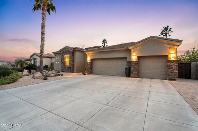 view of front of home featuring driveway, a garage, stone siding, and stucco siding