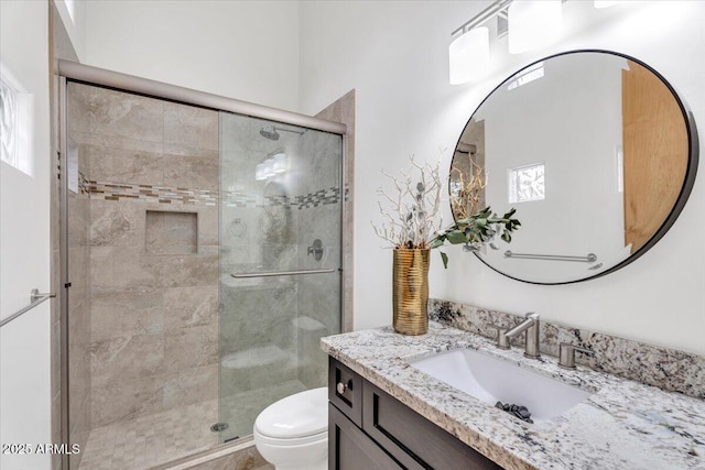 bathroom with toilet, a stall shower, and vanity