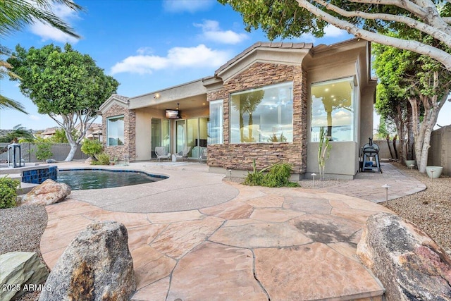 back of property featuring stucco siding, stone siding, a patio, and a fenced backyard