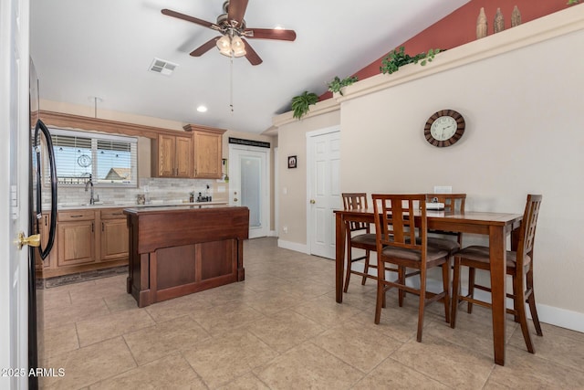 kitchen with lofted ceiling, sink, black refrigerator, ceiling fan, and decorative backsplash