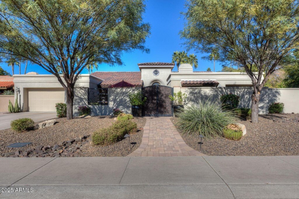 view of front facade with stucco siding, driveway, fence, an attached garage, and a tiled roof