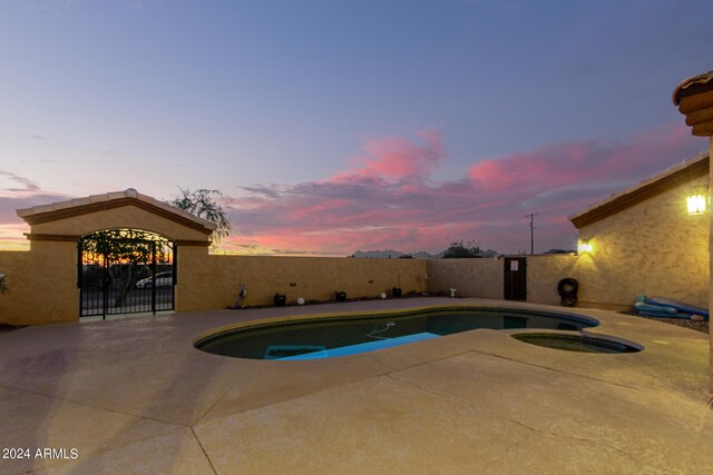 pool at dusk featuring a patio area