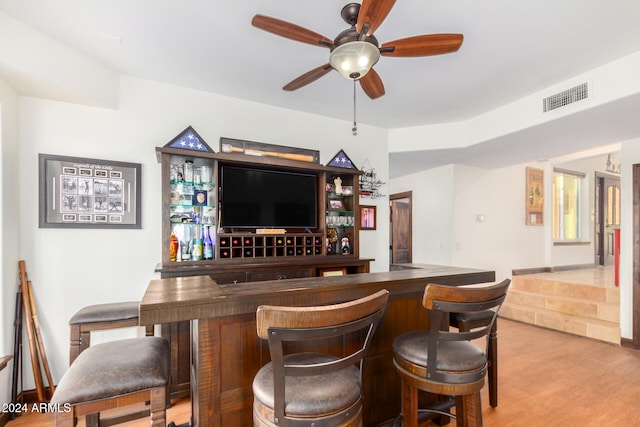 bar featuring light wood-type flooring and ceiling fan