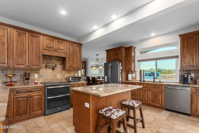 kitchen with tasteful backsplash, a breakfast bar, light stone countertops, appliances with stainless steel finishes, and a center island