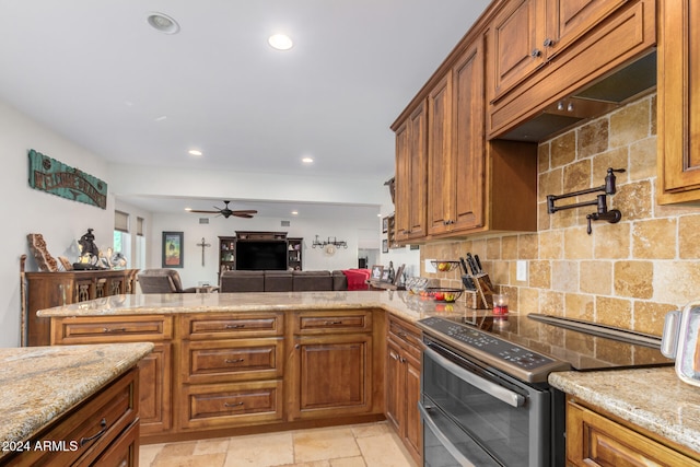 kitchen with light stone countertops, stainless steel electric range oven, kitchen peninsula, and tasteful backsplash