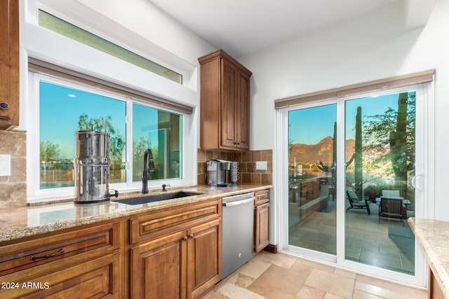 kitchen with tasteful backsplash, light stone countertops, sink, and dishwasher