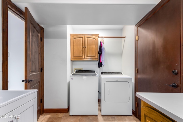 washroom with light tile patterned flooring, washing machine and clothes dryer, and cabinets