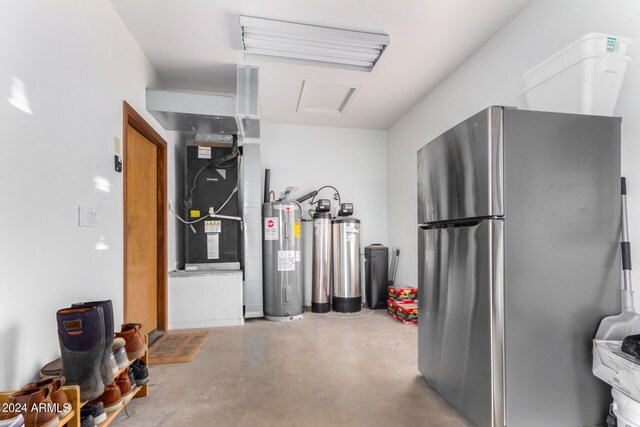 garage with heating unit, stainless steel refrigerator, and water heater