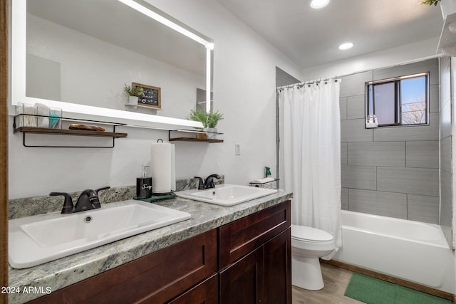 bathroom with toilet, double vanity, a sink, and wood finished floors