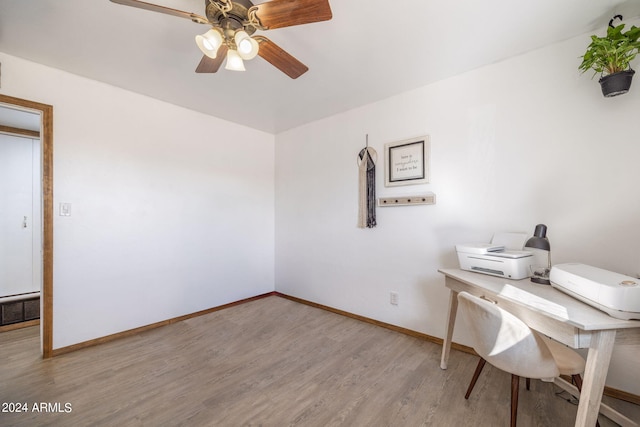 home office with a ceiling fan, light wood-type flooring, visible vents, and baseboards