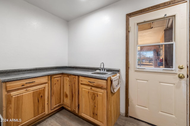 kitchen featuring brown cabinetry, dark countertops, and a sink