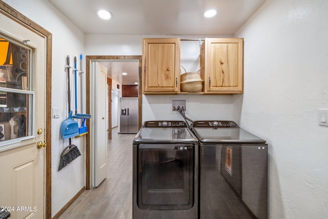 laundry area with washing machine and clothes dryer, cabinets, and light hardwood / wood-style flooring