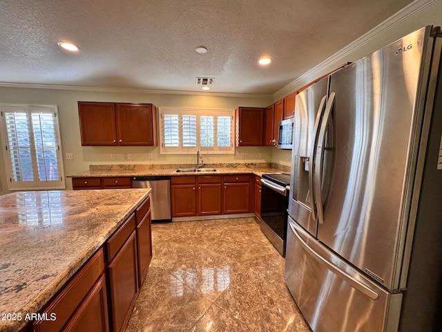 kitchen with light stone counters, sink, stainless steel appliances, and a textured ceiling