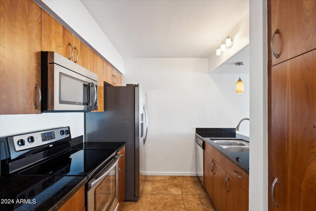 kitchen with light tile patterned floors, stainless steel appliances, sink, and pendant lighting