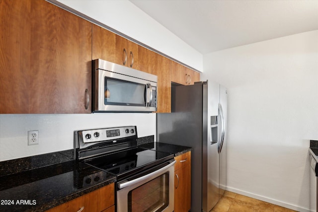 kitchen featuring dark stone counters, stainless steel appliances, and light tile patterned flooring