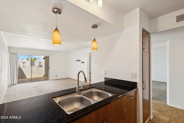 kitchen featuring light colored carpet, pendant lighting, and sink