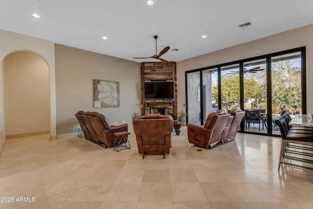 living room with a stone fireplace and ceiling fan