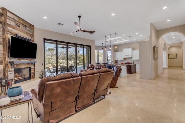 living room with a large fireplace and ceiling fan