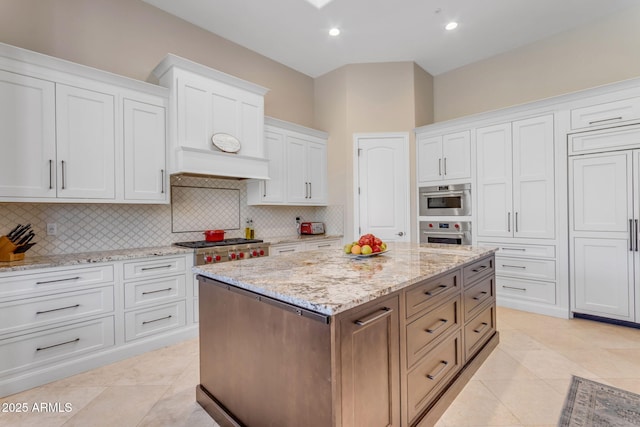 kitchen with white cabinetry, light stone counters, tasteful backsplash, and a kitchen island