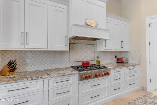 kitchen featuring light tile patterned flooring, white cabinetry, decorative backsplash, stainless steel gas cooktop, and custom range hood