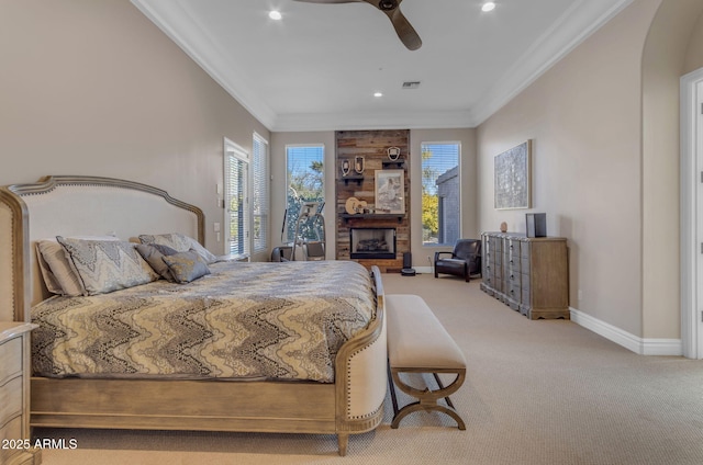 carpeted bedroom with multiple windows, crown molding, ceiling fan, and a fireplace