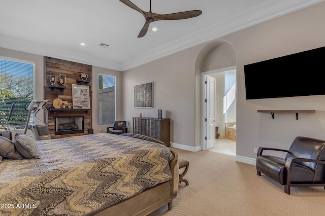 carpeted bedroom with ornamental molding, ensuite bathroom, ceiling fan, and a fireplace