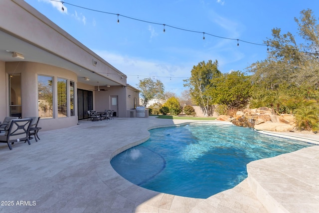 view of swimming pool featuring a patio area, ceiling fan, and exterior kitchen