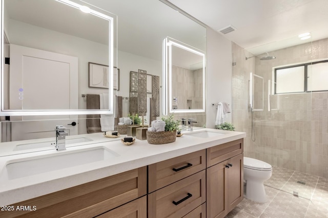 full bath with toilet, tiled shower, double vanity, and tile patterned floors