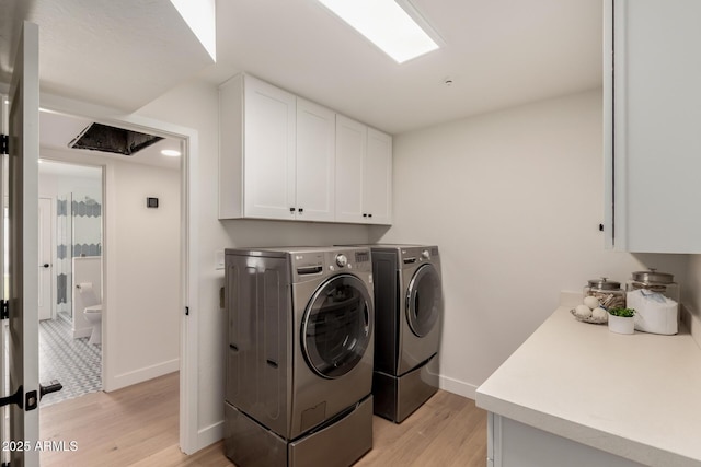 laundry area featuring cabinet space, washing machine and clothes dryer, light wood-style flooring, and baseboards