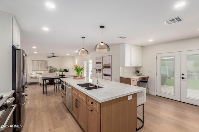 kitchen featuring french doors, a sink, open floor plan, appliances with stainless steel finishes, and light wood-style floors