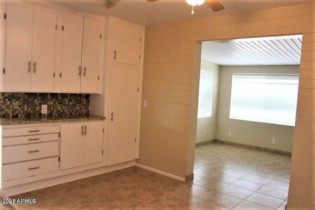 11201 W Missouri Ave, Youngtown, AZ 85363 - kitchen featuring ceiling fan, dark stone counters, white cabinetry, baseboards, and decorative backsplash