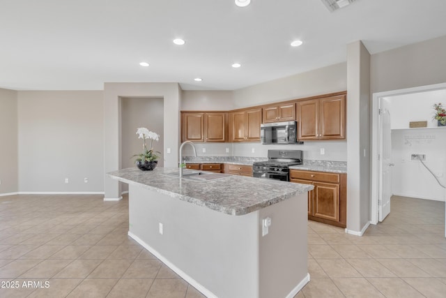 kitchen with sink, black gas range, a center island with sink, and light tile patterned floors