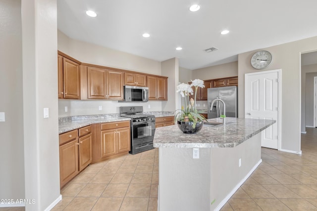 kitchen featuring stainless steel appliances, sink, a kitchen island with sink, and light tile patterned floors