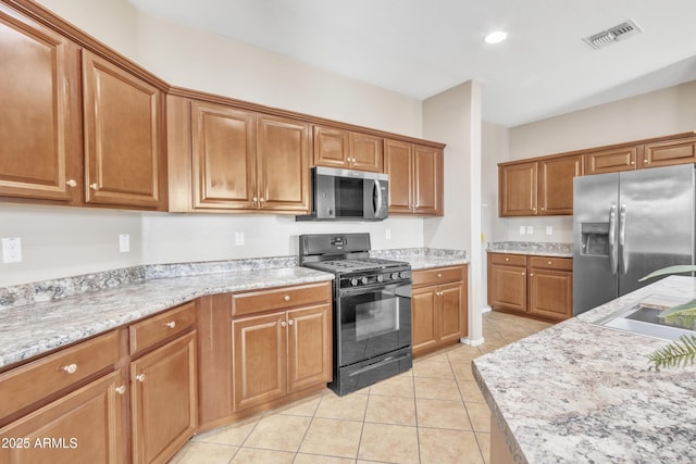 kitchen with sink, light tile patterned floors, stainless steel appliances, and light stone countertops