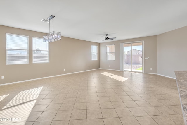 tiled spare room with ceiling fan with notable chandelier