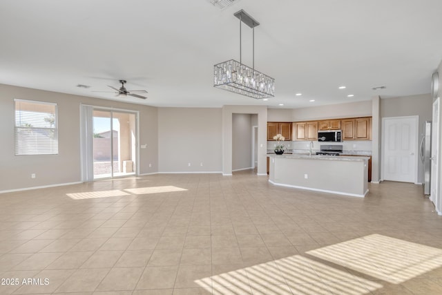 unfurnished living room featuring sink, light tile patterned floors, and ceiling fan